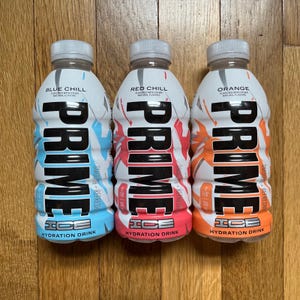 May include: Three 500ml bottles of Prime Hydration drink. The bottles are labelled with the flavours Blue Chill, Red Chill, and Orange. The bottles are all white with black text and a blue, red, and orange design.