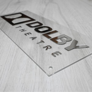 May include: A silver acrylic sign with the text "Dolby Theatre" in raised letters.