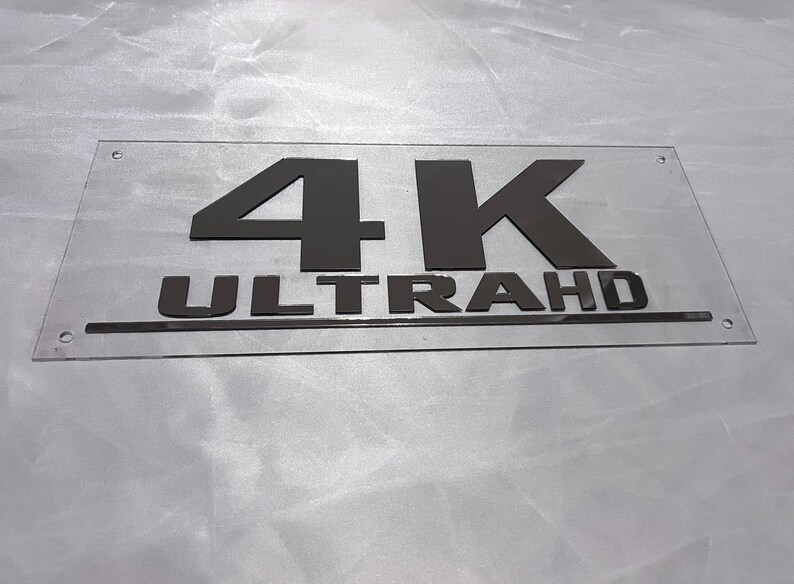 May include: A clear acrylic sign with black lettering that reads "4K ULTRA HD".