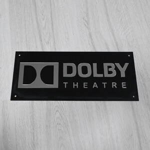May include: A black metal sign with silver lettering that reads "Dolby Theatre".