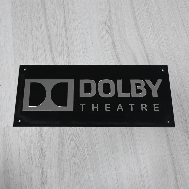 May include: A black metal sign with silver lettering that reads "Dolby Theatre".