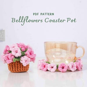 May include: A crochet coaster pot with pink bellflower detailing. A glass of water sits on a matching coaster. The text "PDF PATTERN Bellflowers Coaster Pot" is visible.