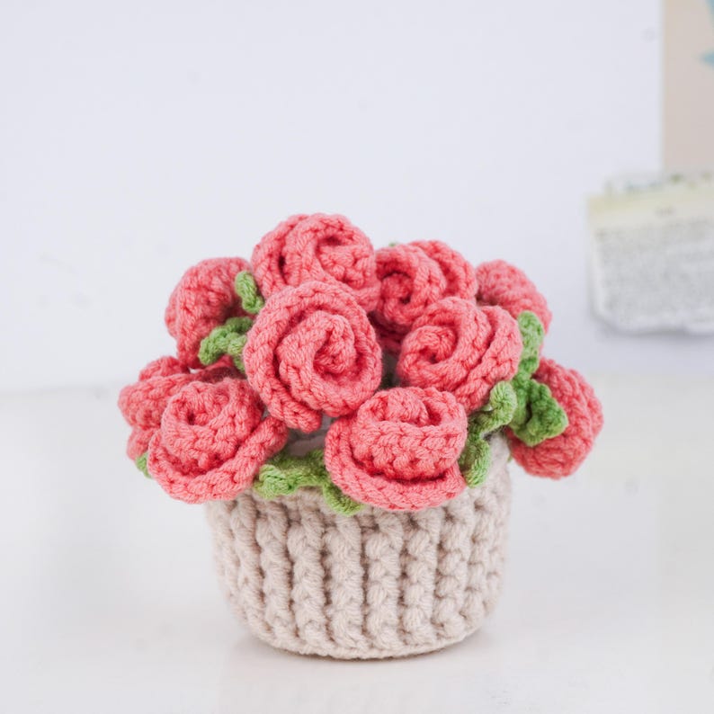 Puede incluir: Un ramo de rosas rosas con hojas verdes en una cesta de ganchillo beige. Las flores hechas a mano est&aacute;n bien enrolladas y dispuestas para crear una exhibici&oacute;n completa y texturizada. La cesta tiene un dise&ntilde;o acanalado.