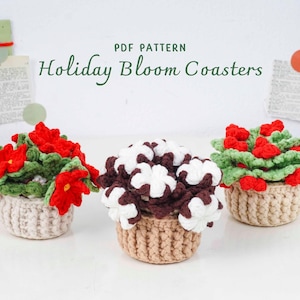 Könnte beinhalten: Drei handgefertigte Häkeluntersetzer in Form kleiner Blumenarrangements. Die Untersetzer zeigen rote, weiße und braune Blumen mit grünen Blättern, in beige Häkeltöpfen. Der Text "Holiday Bloom Coasters" ist sichtbar.