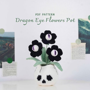 May include: A crocheted flower pot with three black flowers, each with a purple and white eye-like center. The white pot has a skull design. The text "Dragon Eye Flowers Pot" is visible.