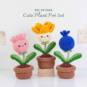 May include: Three crocheted flower pot sets. The flowers are pink, yellow, and blue, each with a smiling face. The pots are brown and sit on a white surface. The text "PDF PATTERN Cute Plant Pot Set" is at the top.
