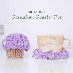 May include: A crocheted coaster pot and coaster set. The coaster pot is shaped like a flower arrangement with purple and white flowers, and a tan basket. The coaster is a ring of purple flowers. A glass cup sits on the coaster. Text reads "Carnation Coaster Pot".