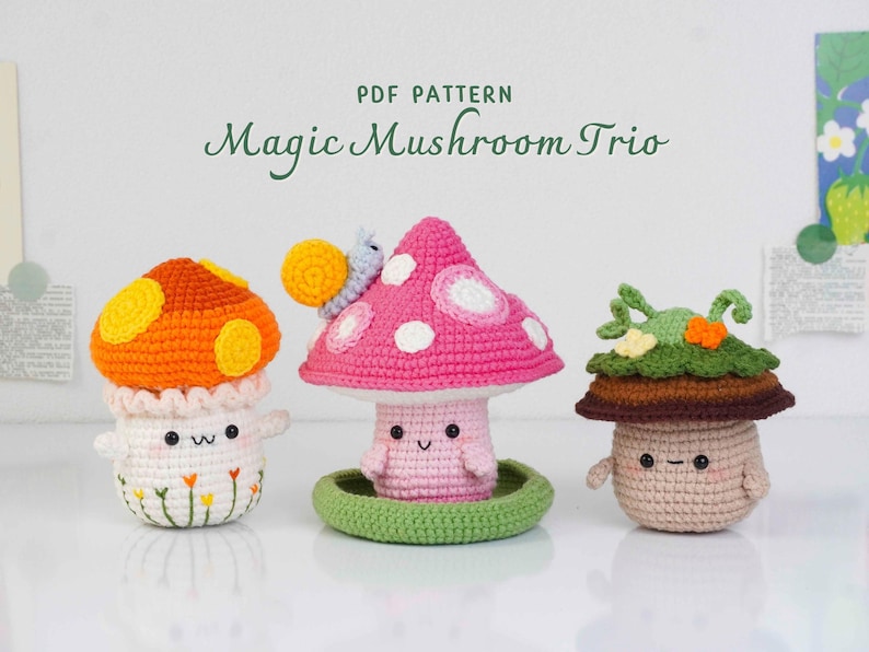 May include: Three crocheted mushroom figures in orange, pink, and brown with smiling faces. The orange mushroom has yellow spots, the pink one has white spots and a snail, and the brown one has green leaves. The text "PDF PATTERN Magic Mushroom Trio" is at the top.