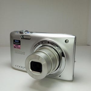 Cámara Nikon Coolpix S2700 plateada de 16 MP con tarjeta de memoria de 64 GB