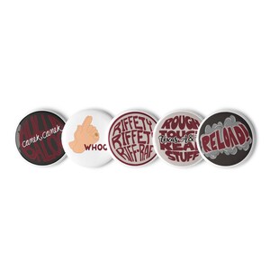 May include: Five round buttons with various designs and text. One button has the text "camek, camek, salo" in red on a black background. Another features a hand gesture with the word "WHOC". Other buttons have text like "RIFFETY RIFFET RIFF-RAF".