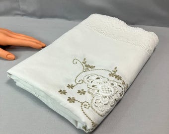 Könnte beinhalten: Weiße Tischdecke mit zarter Spitzenborte und gesticktem Blumendesign in Goldfaden.
