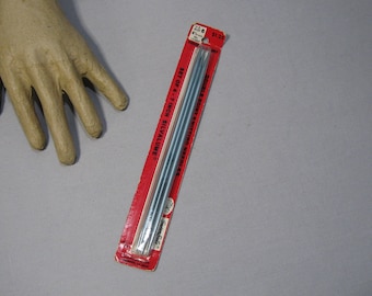 May include: A set of four 7-inch Silvalume double-point knitting needles in a red and white package. The package indicates the needles are size 6, 4.0 mm, and 1107. The needles are a light blue color.
