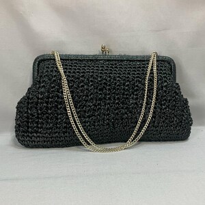 May include: A black crocheted evening bag with a silver chain strap.