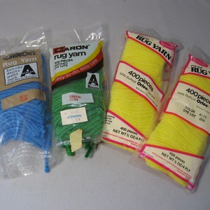 May include: Four packages of pre-cut rug yarn in blue, green, and yellow. The packages are labeled "CARON Rug Yarn", "CARON rug yarn", "RUG YARN", and "RUG YARN".