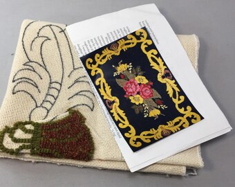 Könnte beinhalten: Ein Rug-Hooking-Bastelset mit einer Leinwand mit einem floralen Design und teilweise fertiggestelltem Rug-Hooking. Eine gedruckte Karte zeigt ein fertiges Rug-Design mit marineblauem Hintergrund, goldenem Rand und Blumenarrangement. Anweisungen sind enthalten.