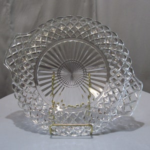 May include: A clear glass serving plate with a diamond pattern and a scalloped edge. The plate is on a gold metal stand.