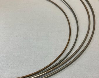 Puede incluir: Cuatro aros metálicos de diferentes tamaños, todos hechos del mismo alambre fino de color plateado. Los aros están ligeramente oxidados y tienen un aspecto desgastado y vintage.