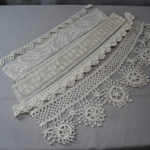 Op de afbeelding: Drie stukken witte gehaakte kant. De kant is delicaat en ingewikkeld met verschillende patronen.