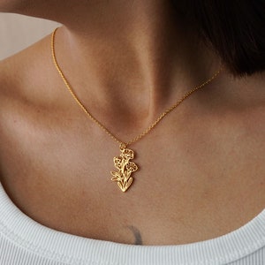 May include: A gold necklace with a delicate floral pendant. The pendant is a cutout design of a flower with multiple petals.
