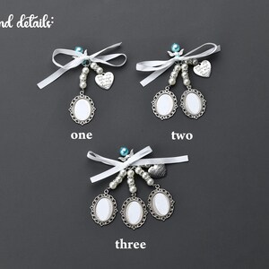 May include: Three white satin ribbon and pearl charm keychains with silver oval photo frames. The charms include a heart with the text "Forever and Always" and a small angel.