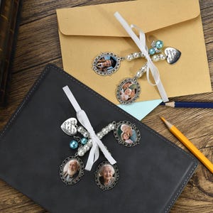 May include: Two white ribbon bookmarks with silver charms and beads. The charms feature photos of couples and the text "In loving memory of our angel".
