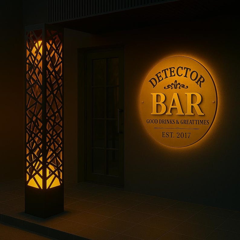 May include: Exterior of a bar at night. A tall, geometric, illuminated pillar is on the left. A round, illuminated sign reads "Detector Bar" with the text "Good Drinks & Great Times" and "Est. 2017".