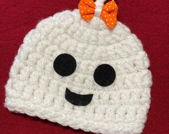 May include: A white crocheted ghost hat with black felt eyes and a smile. An orange polka dot bow is attached to the top of the hat. The text "Faithfully Crocheting" is written in cursive at the bottom.