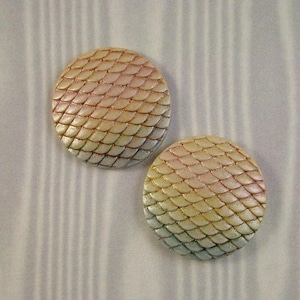 May include: Two round, iridescent, ceramic buttons with a scale pattern in shades of pink, yellow, and green.