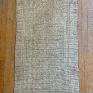 May include: A light gray rug with a subtle pattern and a fringed border. The rug is made of a woven material and has a distressed look.
