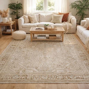 May include: A living room scene featuring a large, beige patterned rug with a distressed look. The room includes white sofas, wooden coffee table, and decorative pillows. Wicker baskets and plants add to the cozy, neutral aesthetic.