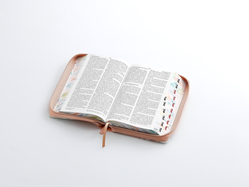 May include: An open book with a pink cover and colorful patterned edges. The pages are filled with text.