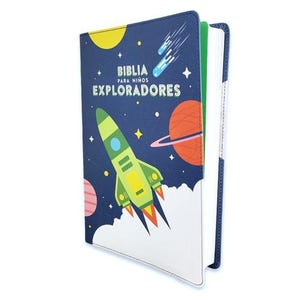 May include: A children's Bible with a space theme. The cover is navy blue with a rocket ship, planets, and stars. The text "BIBLIA PARA NIÑOS EXPLORADORES" is printed on the cover. The spine is blue, and the pages are white.