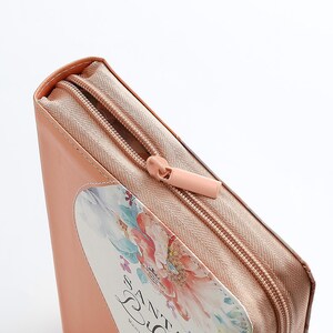May include: A peach-colored zippered pouch with a floral design and the text "The Zest" printed on the front.