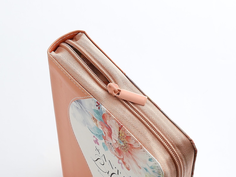 May include: A peach-colored zippered pouch with a floral design and the text "The Zest" printed on the front.