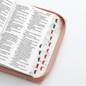 May include: A close-up of a pink zippered Bible cover with a floral pattern. The cover has a zipper closure and a ribbon bookmark. The Bible is open to the book of Job, chapter 30, verses 29-31.