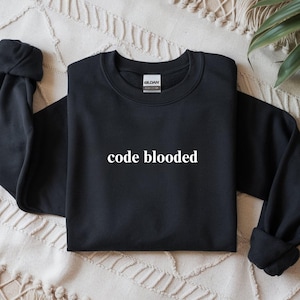May include: Black crewneck sweatshirt with the text "code blooded" in white. The sweatshirt is made of a soft material and has a classic, casual style. The Gildan brand tag is visible on the back of the neck.