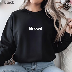 May include: Black sweatshirt with the word "blessed" in white, centered on the chest. The sweatshirt is a solid black color. The word "Black" is in the top left corner.