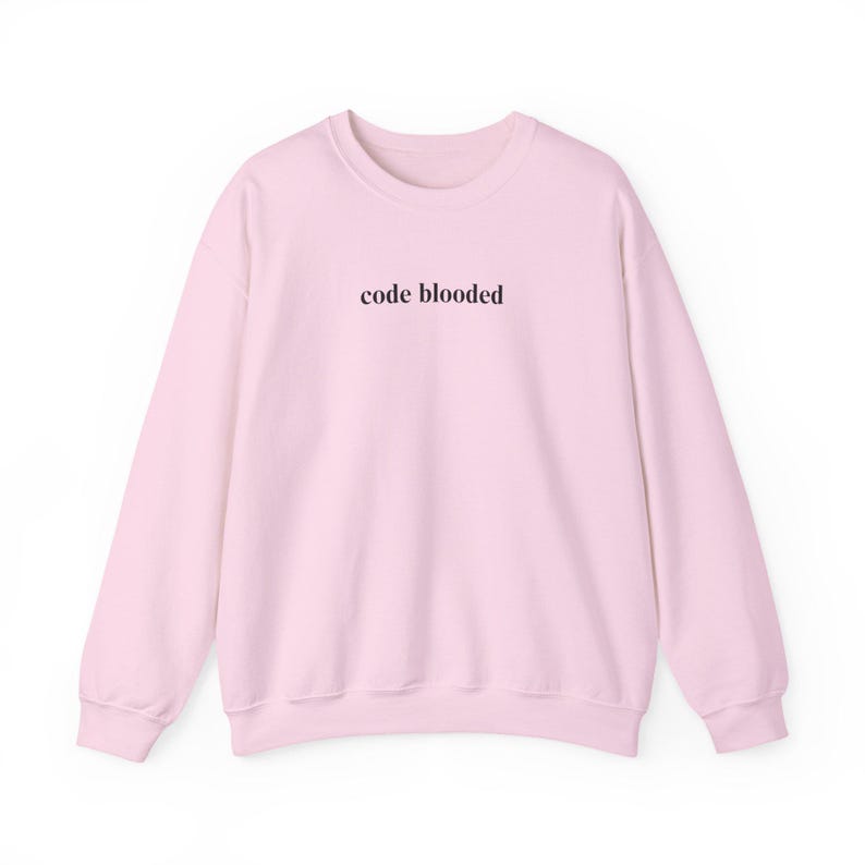 May include: A light pink sweatshirt with the text "code blooded" in a dark brown font across the chest. The sweatshirt has a crew neck and long sleeves, and is made of a soft material.