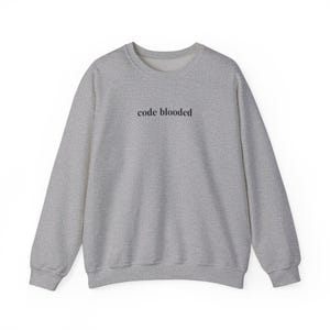 May include: A heather gray sweatshirt with the text "code blooded" printed in black across the chest. The long-sleeved crew neck top is made of a soft material.