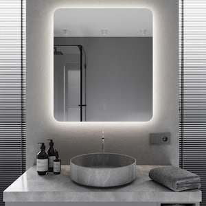 May include: A modern bathroom vanity with a gray countertop, a round gray sink, and a rectangular mirror with a white light around the edge. There are two black bottles with pumps and a smaller black bottle with a dropper on the countertop.