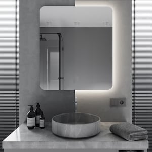 May include: A modern bathroom vanity with a gray countertop, a round gray sink, and two black bottles of liquid soap. The vanity is in front of a large, rectangular mirror with a thin, white light around the edge.