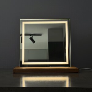 Back side of square tabletop mirror with wooden support stand and clean design