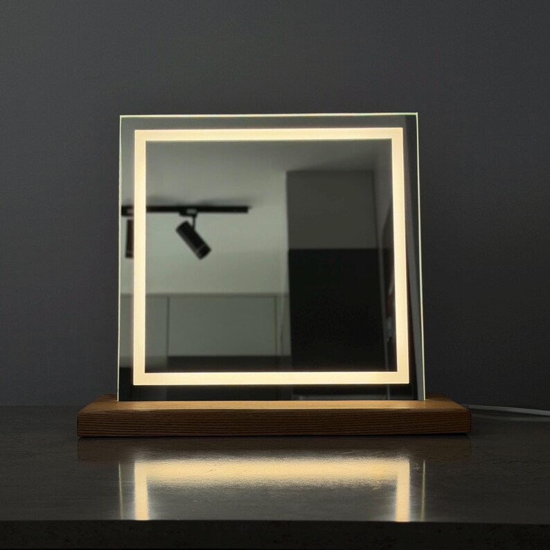 Back side of square tabletop mirror with wooden support stand and clean design