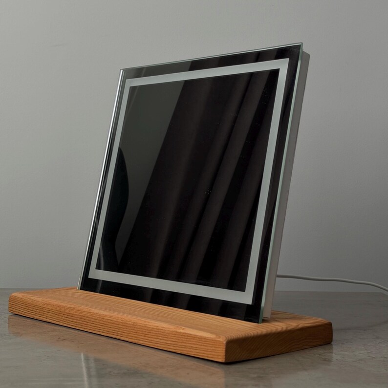 Black reflective mirror on solid oak stand with modern minimalist home decor aesthetic