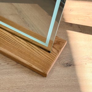 Close-up of tabletop mirror edge and handcrafted wooden stand detail