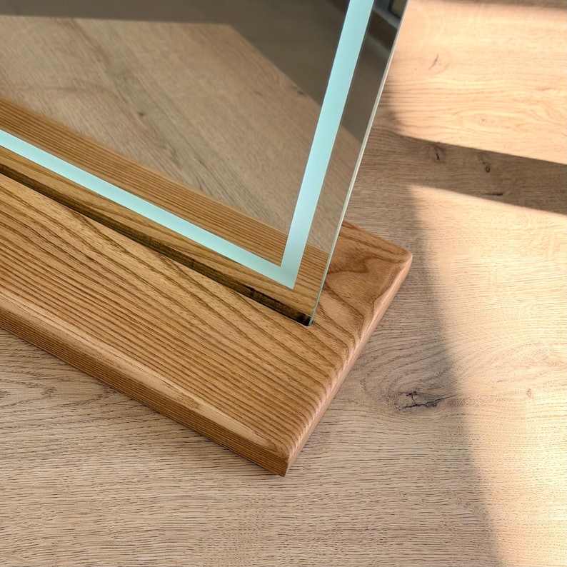 Close-up of tabletop mirror edge and handcrafted wooden stand detail