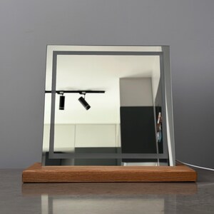 Minimalist vanity mirror with  wood base photographed in modern dark interior