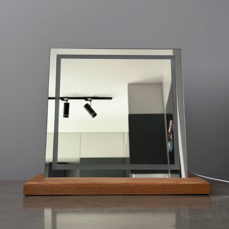 Minimalist vanity mirror with  wood base photographed in modern dark interior