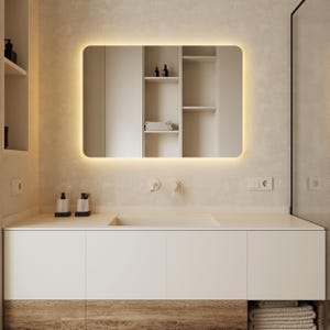 以下が含まれることがあります： 白い洗面台は、白いカウンタートップと白い磁器製のシンクが付いています。洗面台には引き出しが2つと木製のベースがあります。シンクの上に、周囲に光がついた鏡が取り付けられています。シンクの後ろの壁には、白いタオルバーが2つあります。