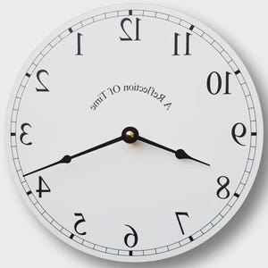 May include: A white round clock with black numerals and hands. The clock face has the text "A Reflection of Time" in a curved font. The clock hands point to approximately 4:40.